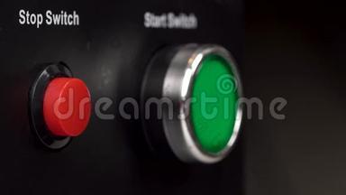 框架中的两个按钮。 绿色启动开关和红色停止开关按钮。 手指按红色停止开关按钮。